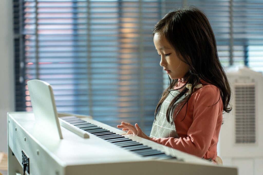 Asian adorable child enjoy playing piano in living room at home.