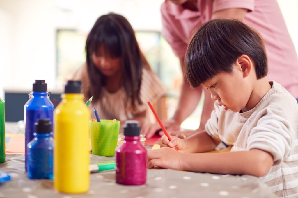 Asian Father With Children Having Fun With Children Doing Craft On Table At Home