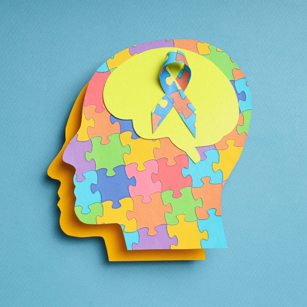 Paper human heads with colorful puzzle pieces on a light background. World autism day concept